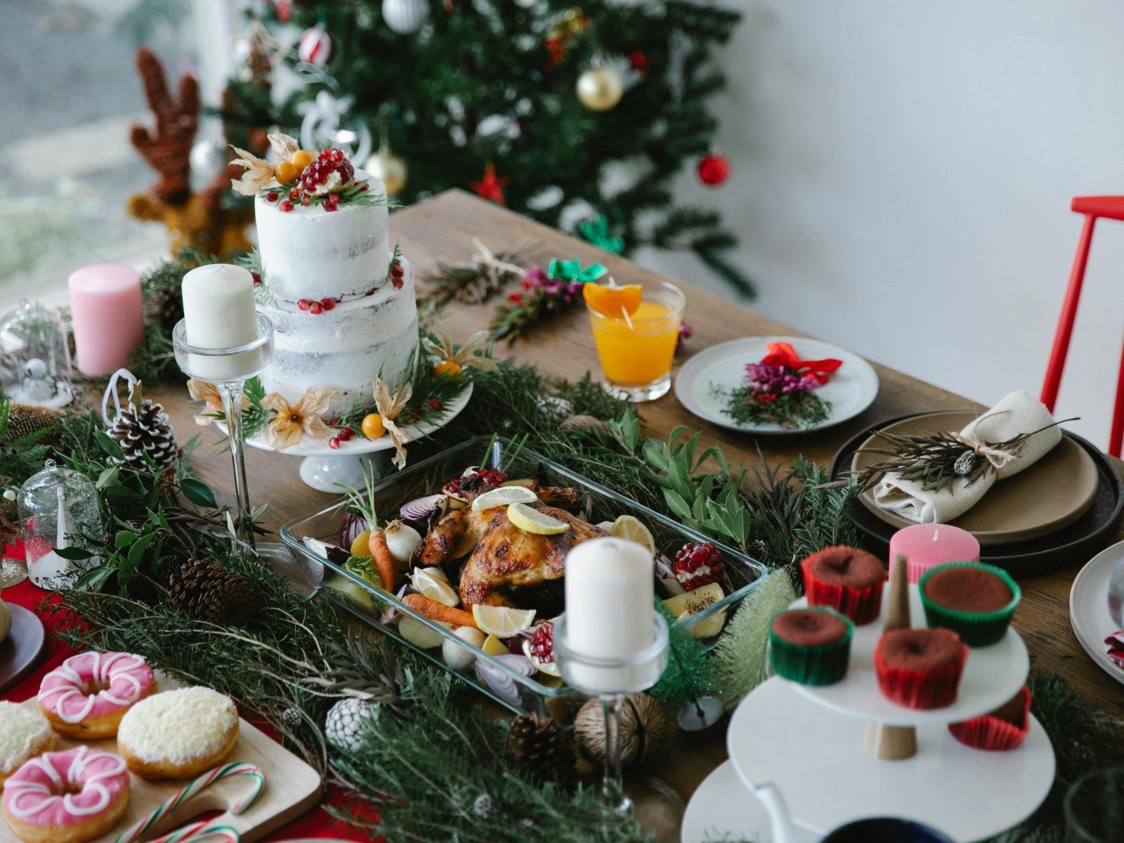 Roasted chicken, a Christmas cake and festive decorations are placed on the table, with a decorated artificial Christmas tree visible in the background.