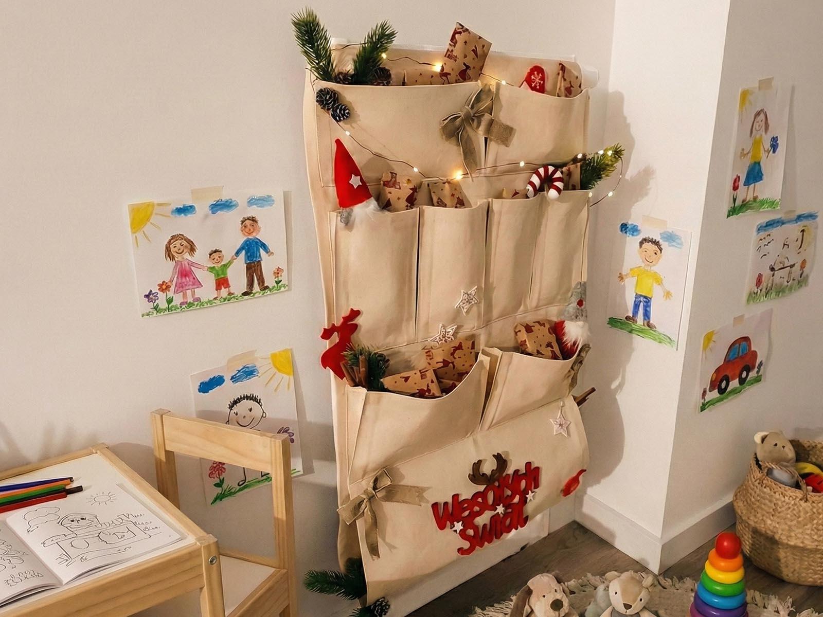 A fabric Advent calendar decorated with FairyTrees&rsquo; artificial Christmas tree twigs and lights hangs in the corner of the children&rsquo;s room.