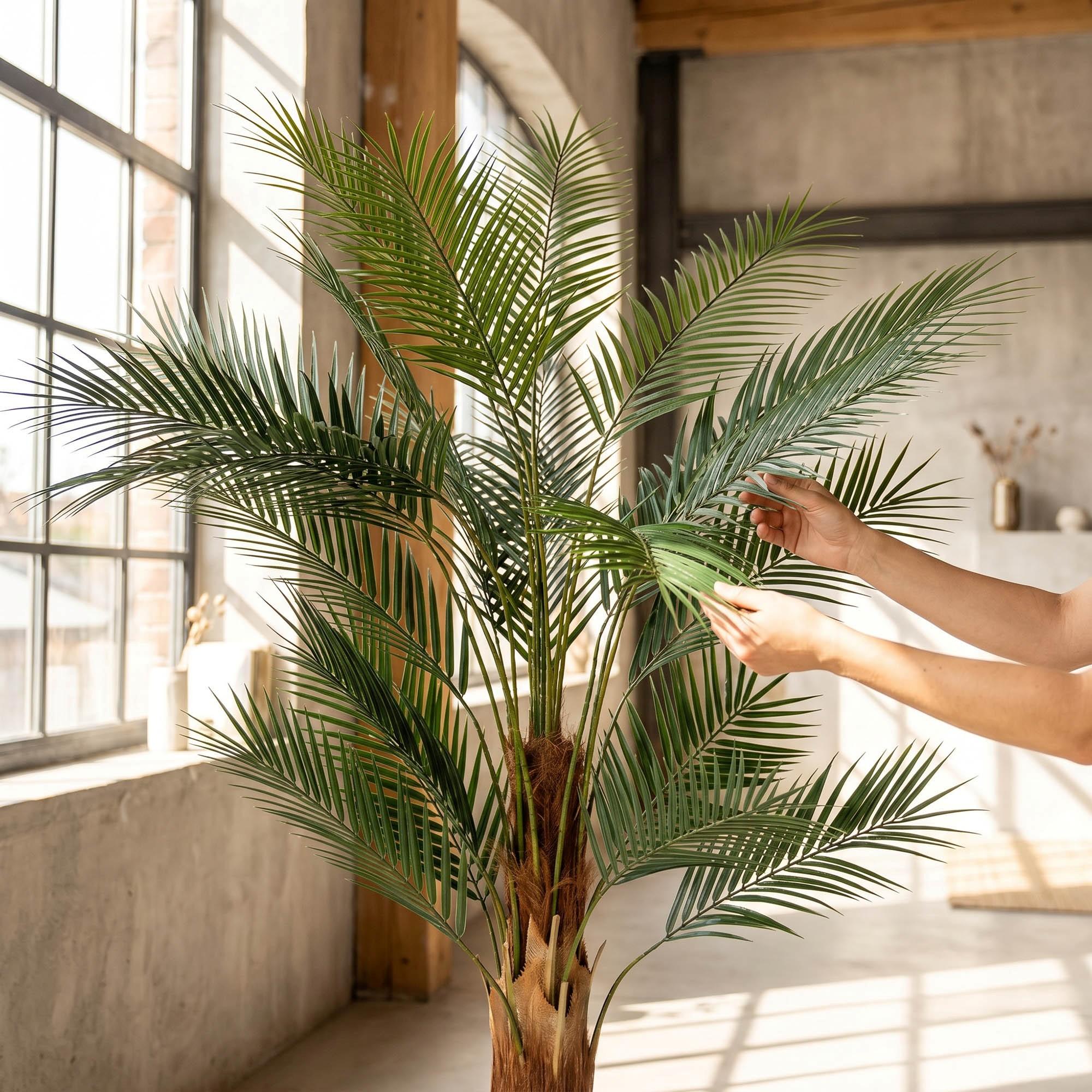 Hands adjust the leaves of the 160 cm FairyTrees artificial monstera on a trunk, highlighting their natural appearance and flexibility.