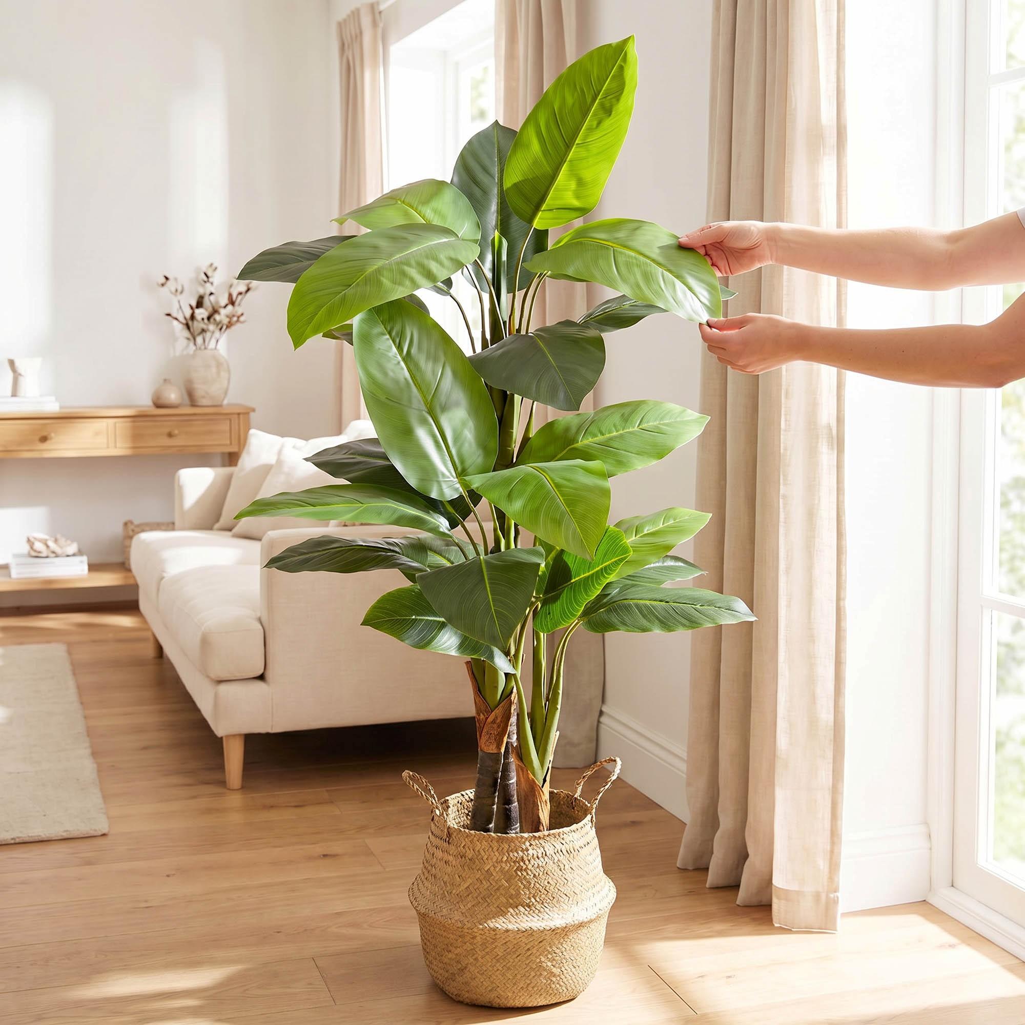 Hands adjust the leaves of the 160 cm FairyTrees artificial monstera on a trunk, highlighting their natural appearance and flexibility.